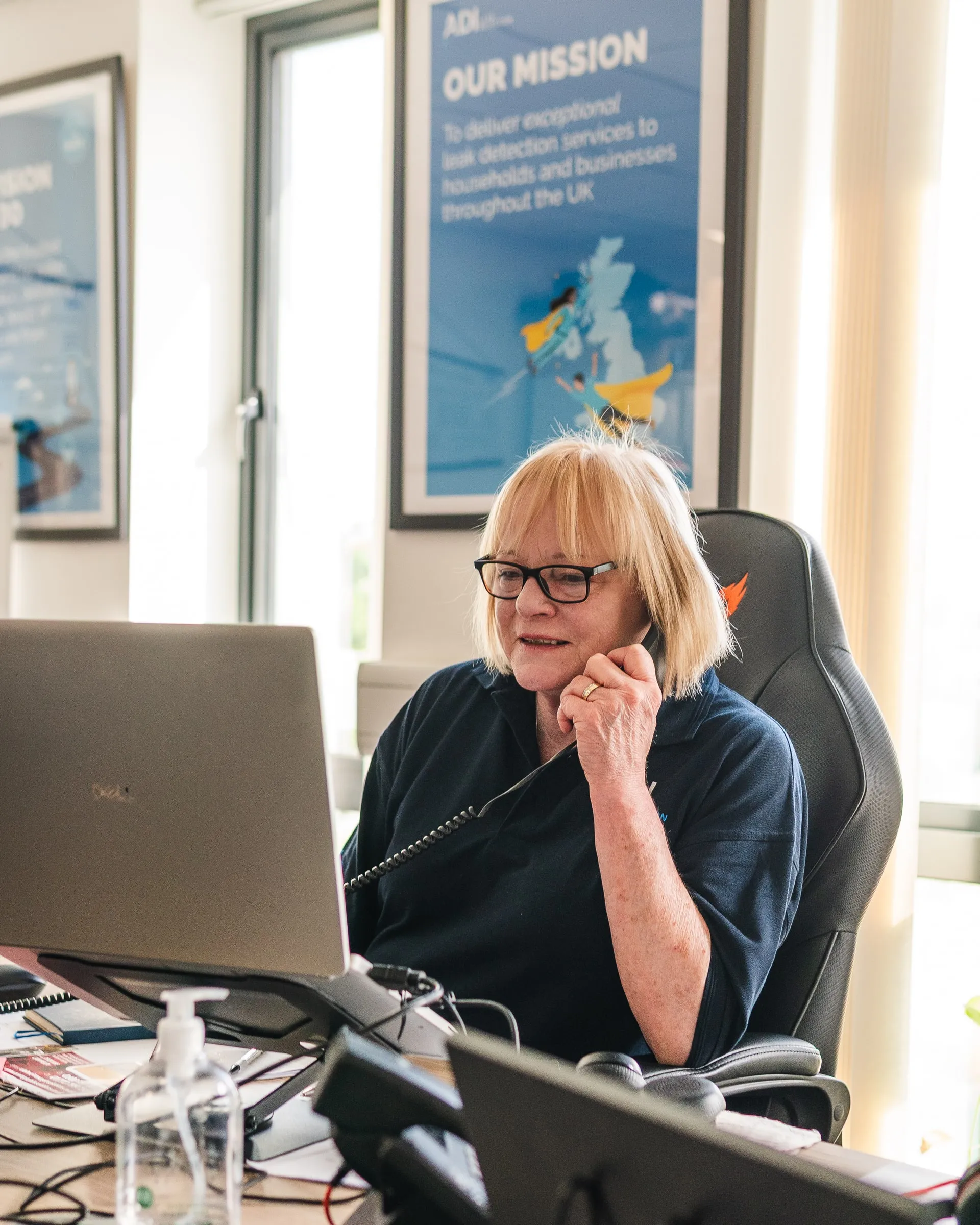 Member of ADI's office team on the phone at her desk, taking a call