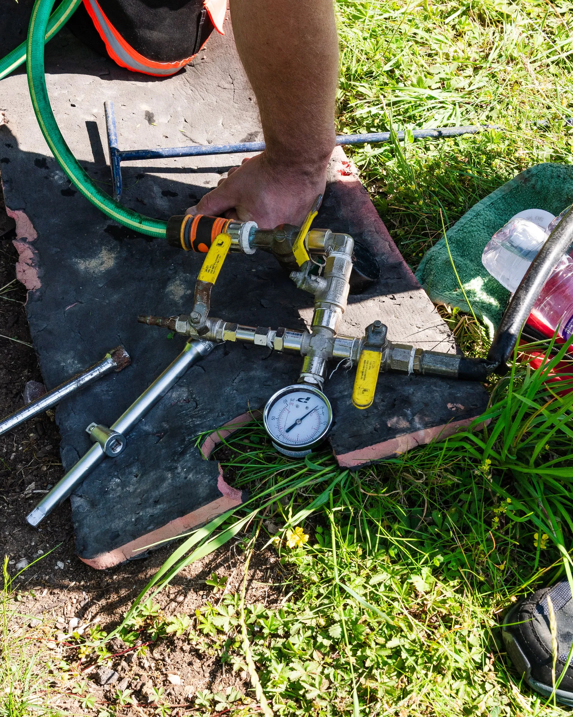 Pressure test manifold with a gauge, valves and hoses laid out on the ground ready to connect